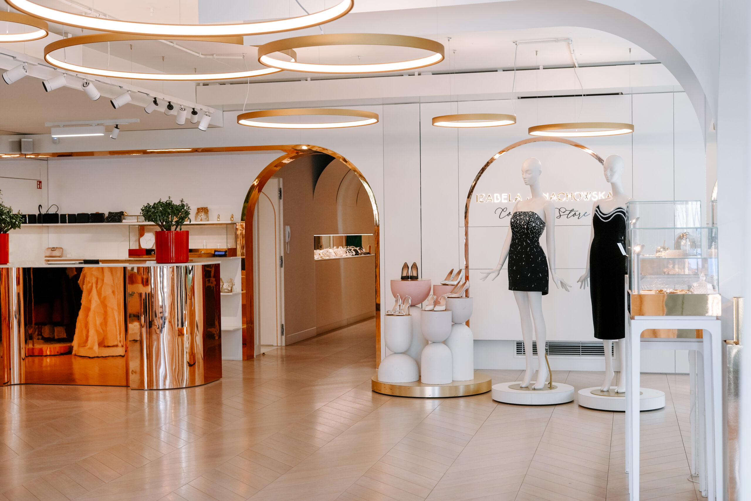 Wnętrze butiku Izabela Janachowska Concept Store z manekinami w czarnych sukniach koktajlowych.